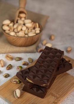 Gourmet chocolate mixed with crunchy kadaif pistachio pieces is beautifully presented on a wooden board, making a perfect treat in Dubai's culinary scene.