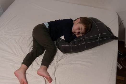 Child sleeping peacefully on bed hugging pillow: napping boy embraces comfort and rest