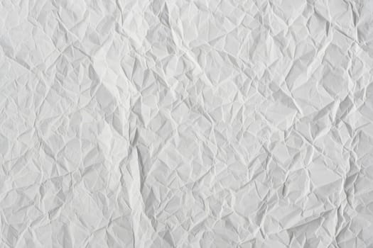 Textured crumpled white paper fills the frame, displaying a variety of intricate folds and creases. This material can be used for backgrounds in crafts or designs, adding depth and character.
