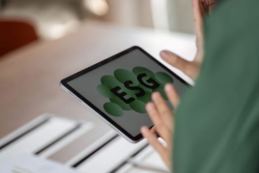 A professional holding a digital tablet showcasing the ESG concept, emphasizing sustainability and environmental responsibility in a modern setting.