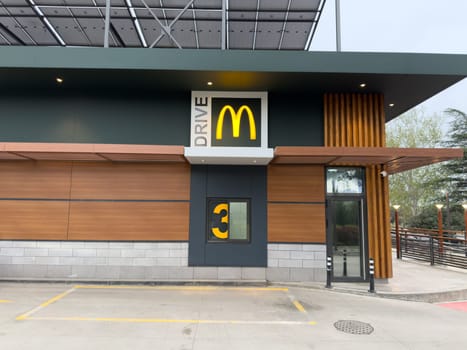 Tbilisi, Georgia, April 13, 2025: Drive Thru window and branding of modern McDonalds restaurant with clean design and illuminated signage. McDrive window for order