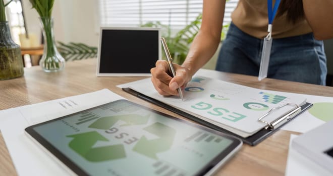 An individual plans ESG sustainability initiatives using a tablet and documents, highlighting a commitment to responsible practices.