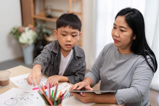 A mother guides her son as they explore educational content on a tablet, emphasizing the importance of technology in learning.
