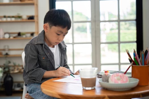 A child engages in artistic activities, drawing with concentration, showcasing creativity and a love for learning in a nurturing environment.