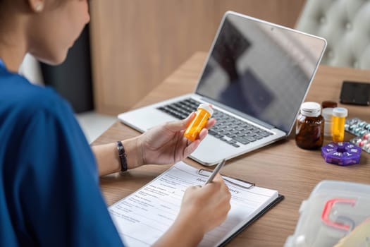 A healthcare provider assessing a patient while taking notes on a laptop for efficient record-keeping.