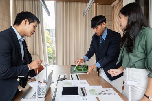 A diverse team collaborates in a strategy session for ESG solutions, actively engaging around a table in a bright, modern office environment.