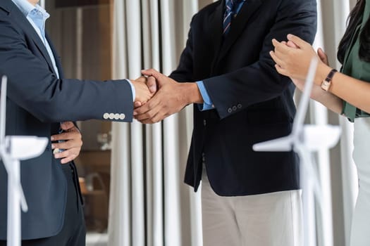 A diverse team signifies a successful ESG partnership with a handshake in a modern office, emphasizing collaboration and mutual goals for sustainability.