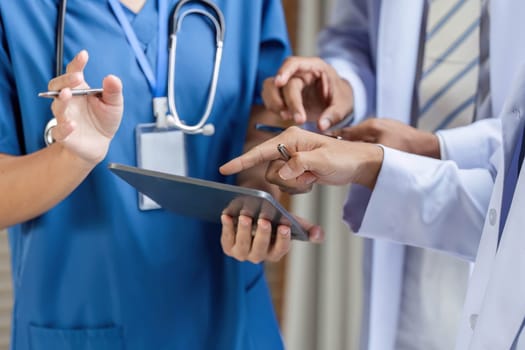 A dedicated doctor collaborating with colleagues, utilizing a tablet to discuss patient information in a healthcare setting, showcasing teamwork and modern technology.
