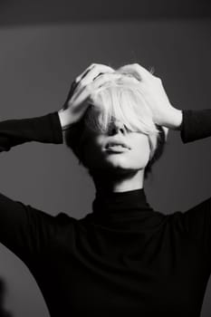 A thoughtful young woman holding her head with both hands, portraying deep emotion. The monochrome setting highlights her features and outfit.