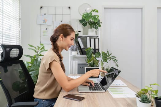 An ESG consultant interacting with a laptop in a serene office space surrounded by greenery, indicating a focus on sustainability.