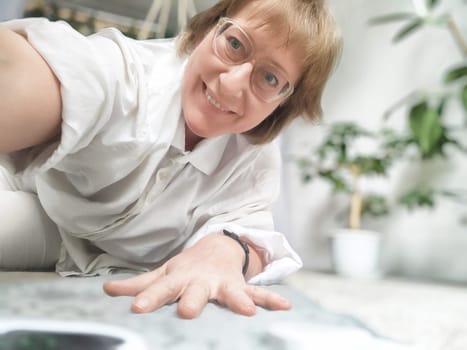 A person stretches and smiles while using an electric heating mat in a comfortable indoor space filled with greenery and warmth.