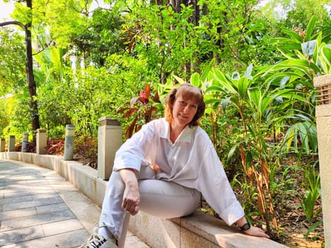 Middle-aged blogger takes a relaxing break in a vibrant garden while on a travel excursion, embracing the beauty of nature.