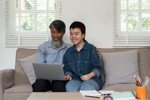 A grandfather and his grandchild enjoy a lighthearted moment while using a laptop together, fostering connection and joy.