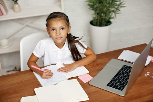 adorable little child girl using laptop computer for studying online learning system. online lesson at home