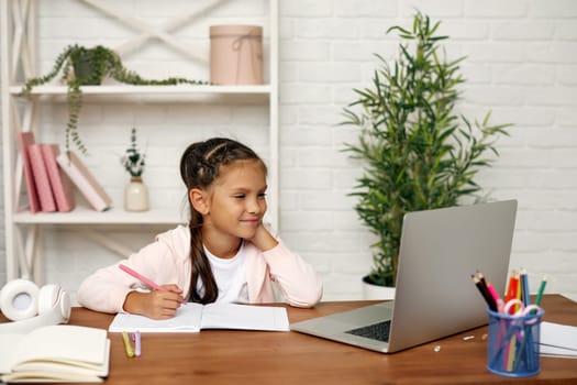 smiling little child girl using laptop for studying online learning system. online lesson at home. social distance during quarantine