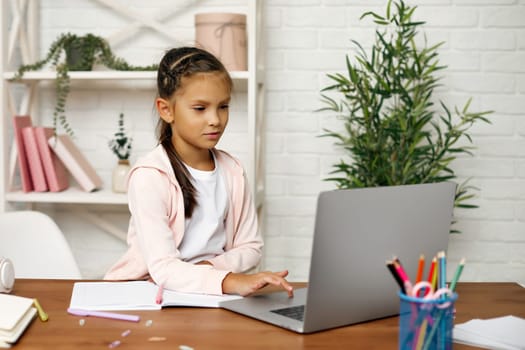 cute little child girl using laptop for studying online learning system. online lesson at home. social distance during quarantine