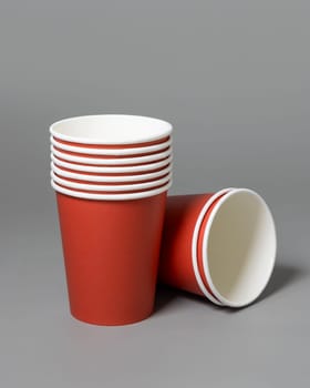 Disposable red paper cups on a dark gray background closeup, mockup with advertising copy space. Empty cardboard coffee cups flat lay. No plastic and sustainable Christmas concept