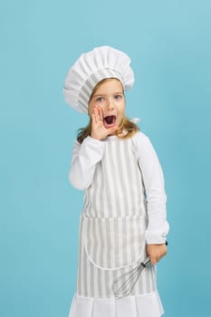 cute little girl in chef hat and apron shouting over blue background. I will tell you the secret of cooking. child dreams of becoming a chef