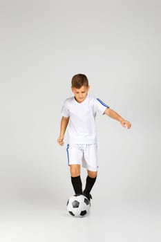 little child boy playing with soccer ball over studio background.
