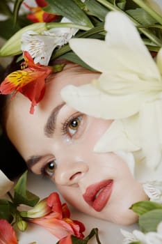 A serene young woman with natural makeup, surrounded by colorful flowers, evokes feelings of spring and renewal, perfect for promoting floral beauty concepts and skincare