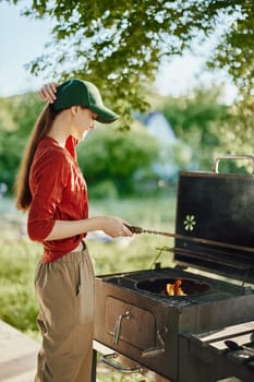 A young woman dressed in a red shirt and cap joyfully grilling at a barbecue in a lush green environment, embodying the spirit of summer and outdoor cooking