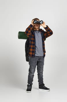 Little boy tourist looking into the distance with binoculars