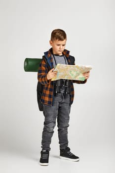 Little boy tourist with backpack holding map. Little boy scout dreams of traveling