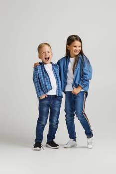 cute little boy and girl in stylish denim clothes. two happy children laughing and having fun