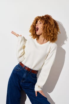 Stylish woman wearing a cozy white sweater and high waisted blue jeans exudes confidence and flair, set against a minimalistic light backdrop, perfect for fashion and lifestyle concepts