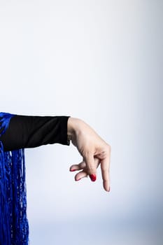 Female hand gesture with blue fabric and red nails against light background.