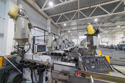 Inside a modern factory, extrusion machines are processing plastic granules, highlighting industrial automation and manufacturing processes
