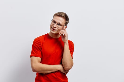 Happy woman with short brown hair, glasses, and a bright red casual t-shirt stands confidently with a smile, striking a thoughtful pose against a neutral background. This engaging portrait captures friendliness, confidence, and positivity, ideal for lifestyle, business, or communication themes.