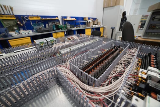 Close-up of electrical cabinet assembly, highlighting organized wiring, relays, and terminals within a workshop environment