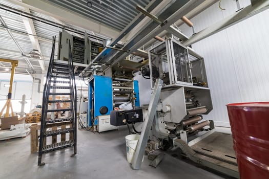 Large industrial printing machine processing large rolls in a printing house, showcasing the manufacturing process
