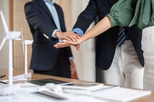 A close-up of diverse hands coming together in a meeting, symbolizing teamwork, partnership, and commitment to sustainability in the professional setting.