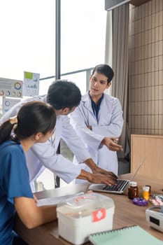 A doctor engaging with colleagues to discuss patient care strategies using a laptop and medical data during a meeting.