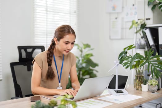 A focused young woman working diligently on her laptop amidst greenery, emphasizing a commitment to ESG and sustainability.