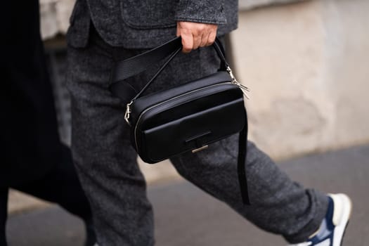 Milan, Italy - January, 14, 2024: Man wears black leather bag. Fashion outfit detail, street style