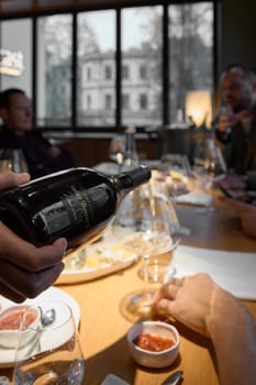 Russia, St.Petersburg, 29 April 2025: Champagne tasting, The sommelier pours sparkling wine from the decanter into a beautiful glass, Wine glasses are on the table, stylish table setting. High quality photo