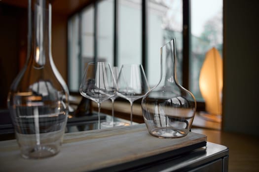 Clean wine glasses are on the table of a special wine cabinet, stylish table setting, ice, bottle of sparkling wine, light from window, decanter and degasser. High quality photo