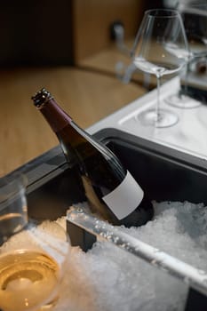 Bottle of champagne is cooled in a niche with ice in the restaurant, local lighting, wine cabinet, decanters for sparkling wine. High quality photo