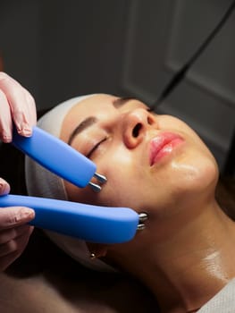Cosmetic procedure for a woman Microcurrents for a woman's face at a beautician. Rejuvenating effect, toned skin, uniform skin color. Close-up, vertical