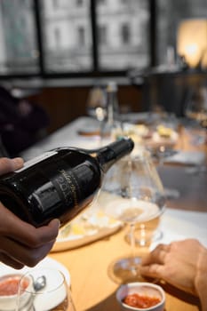 Russia, St.Petersburg, 29 April 2025: Champagne tasting, The sommelier pours sparkling wine from the decanter into a beautiful glass, Wine glasses are on the table, stylish table setting. High quality photo