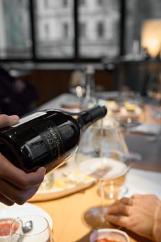 Russia, St.Petersburg, 29 April 2025: Champagne tasting, The sommelier pours sparkling wine from the decanter into a beautiful glass, Wine glasses are on the table, stylish table setting. High quality photo