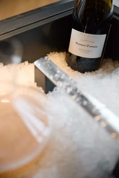 Russia, St.Petersburg, 29 April 2025: Bottle of champagne brand Bonnet-Ponson is cooled in a niche with ice in the restaurant, local lighting, wine cabinet, decanters for sparkling wine. High quality photo