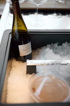 Russia, St.Petersburg, 29 April 2025: Bottle of champagne brand Bonnet-Ponson is cooled in a niche with ice in the restaurant, local lighting, wine cabinet, decanters for sparkling wine. High quality photo