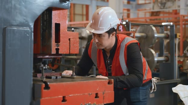Engineer or operator wearing a safety suit working bending metal sheet by sheet press bending machine in workshop, Worker in factory at metal folding machine putting work piece at factory industry