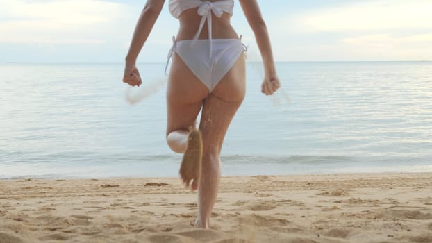 Back view, Young beautiful woman wearing bikini swimsuit running into tropical on sand beach to water, Happy Asian female have fun she run holiday outside, Summer travel vacation concept