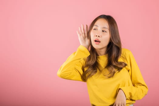 Portrait Asian beautiful young woman teen smiling overhearing listening sound to gossip with attention with her hand on ear studio shot isolated on pink background with copy space hearing gesture