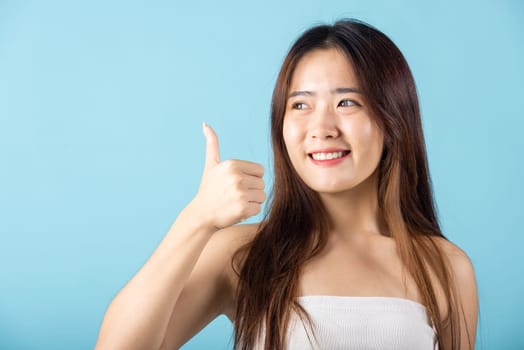 Beauty skin care and cosmetics concept. Happy woman show thumbup like and good studio shot isolated on blue background, Asian young female showing thumb up in approval